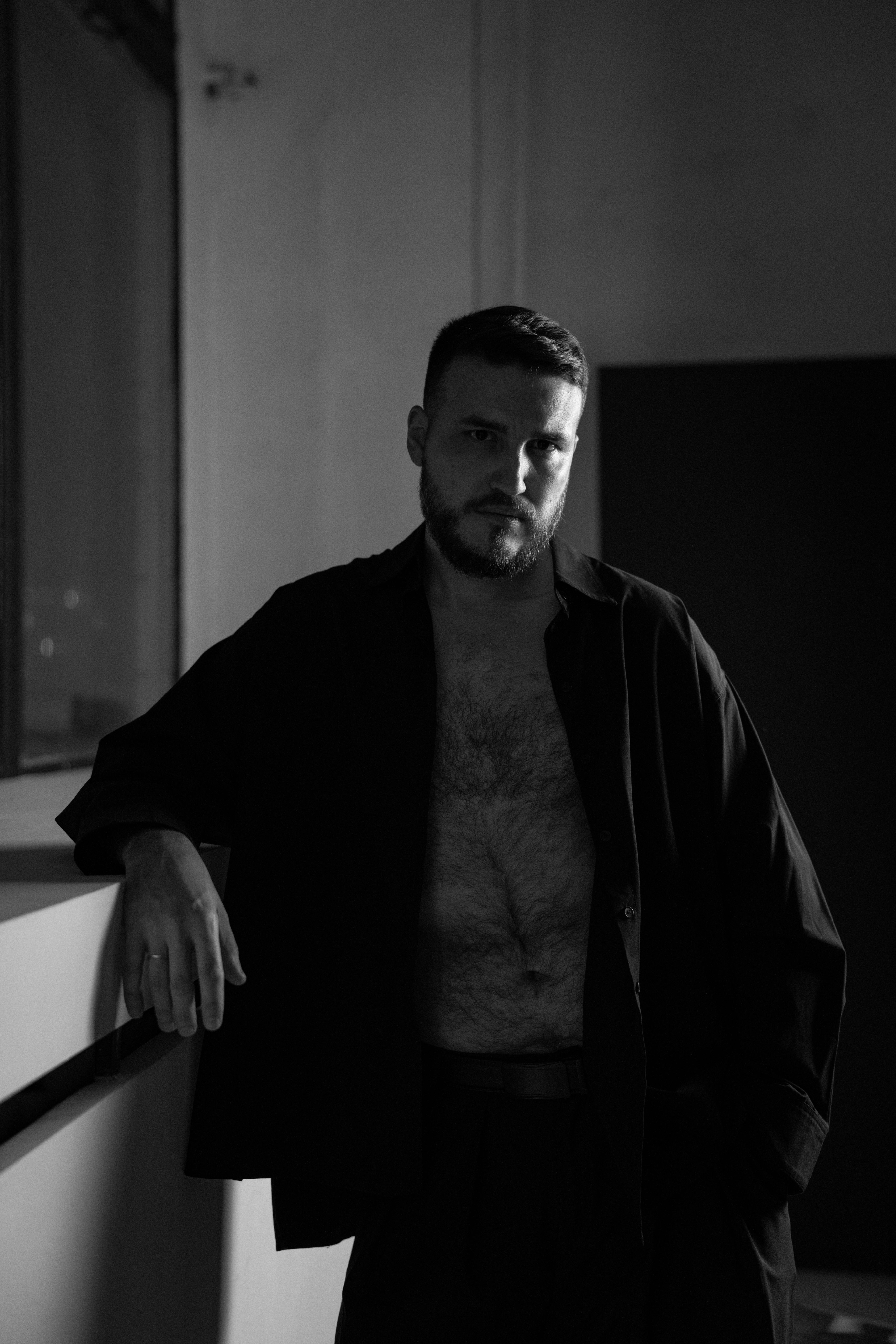 бесплатная Черно-белый портрет мужчины, прислонившегося к стене, создающий мрачную атмосферу. Стоковое фото