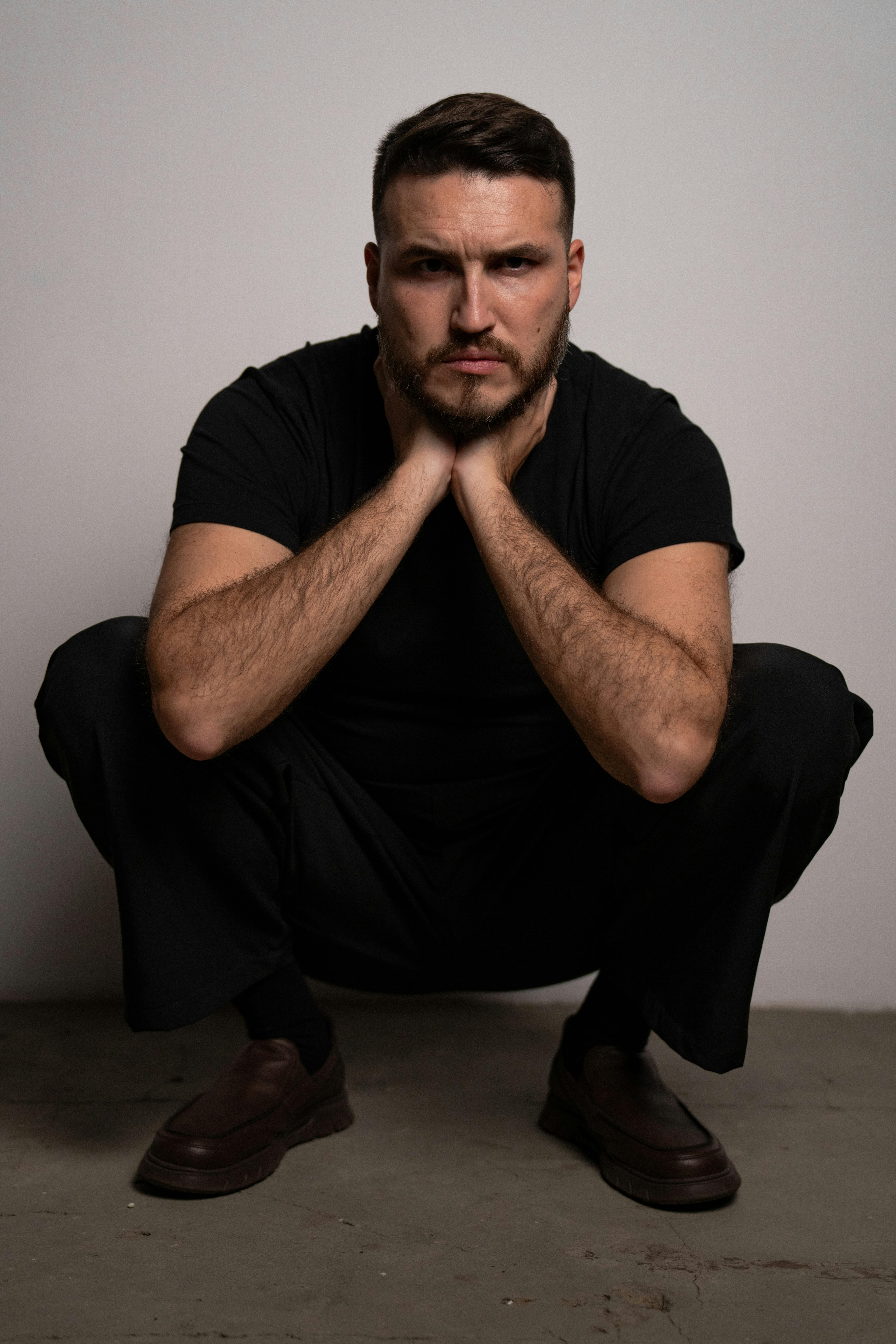 Gratuit Portrait d'un homme accroupi à l'intérieur, affichant confiance et style. Photos