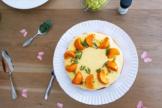 Delicious orange and rosemary cake presented on a wooden table with decorative flowers.