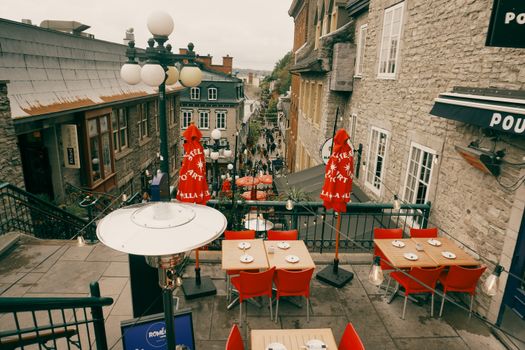 Quaint outdoor café in Old Quebec overlooking a bustling street, showcasing historic architecture and vibrant street life.