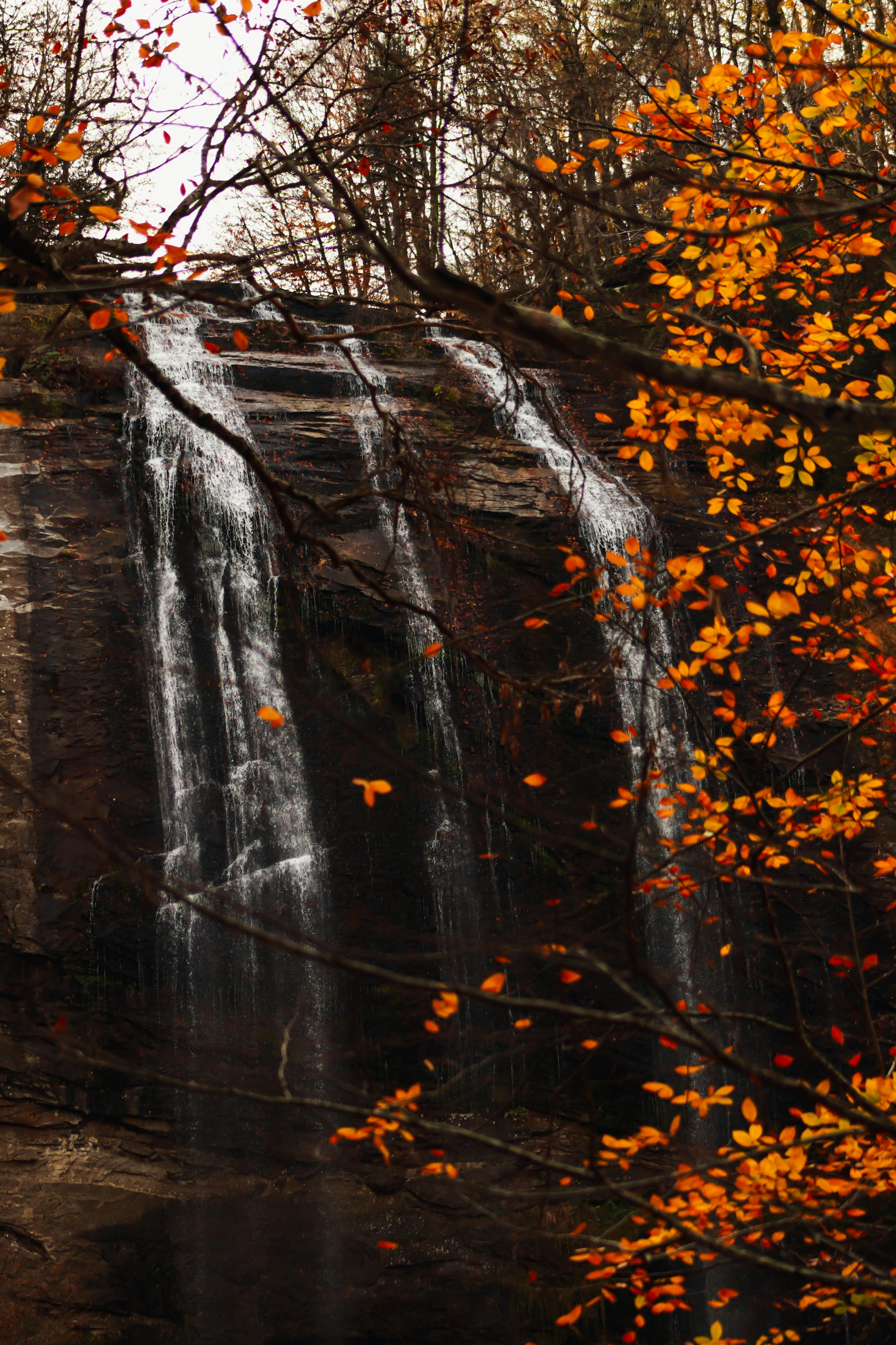 A serene view of a waterfall framed by vibrant autumn leaves in Bursa, Türkiye.