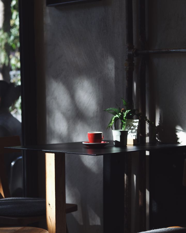 A red coffee cup sitting in dappled window light