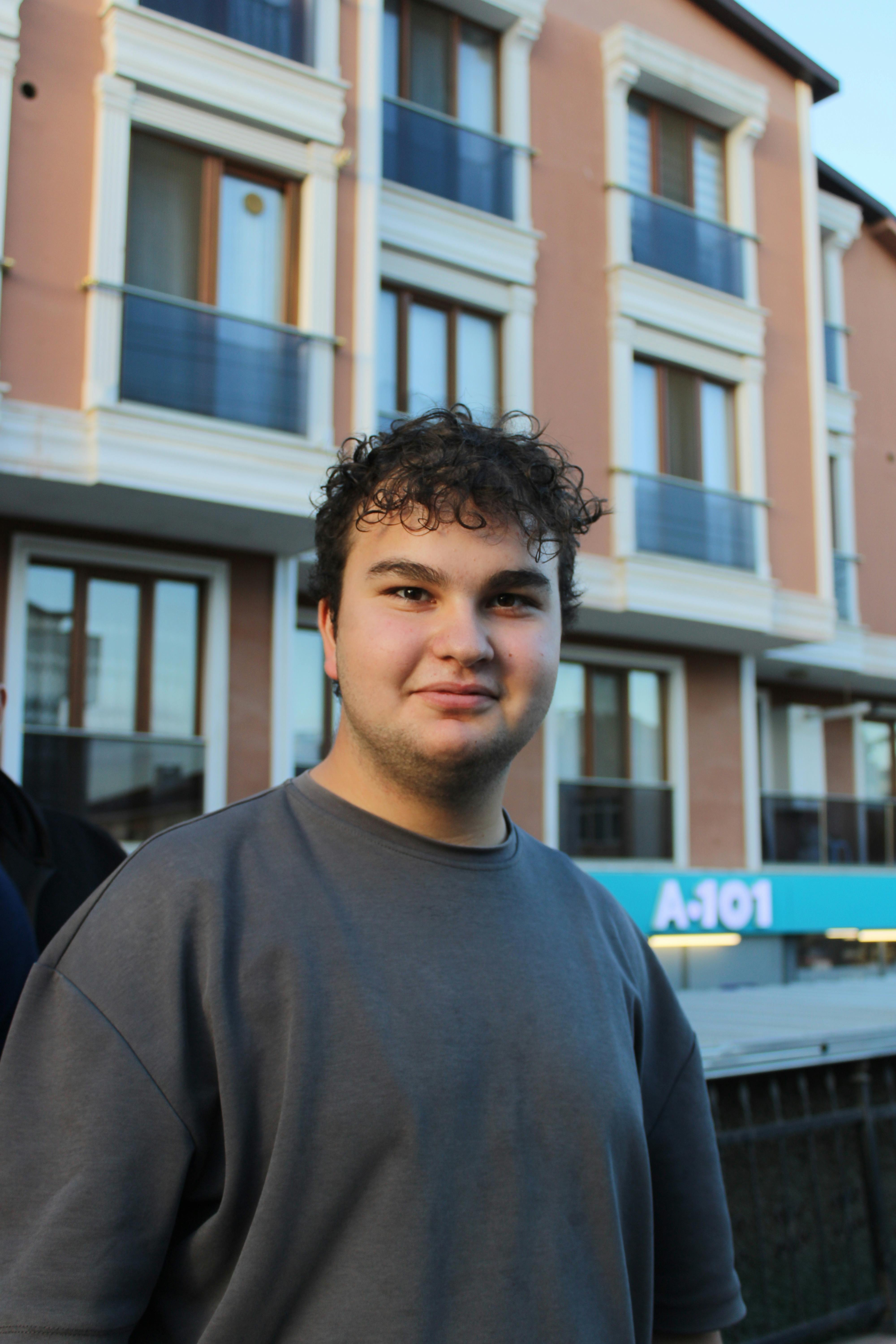 Portrait of a young man standing outdoors in Darica, Turkey with modern architecture in the background.
