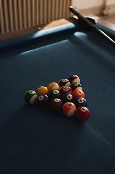 A moody, dramatic close-up of brightly-colored pool balls on a table indoors.