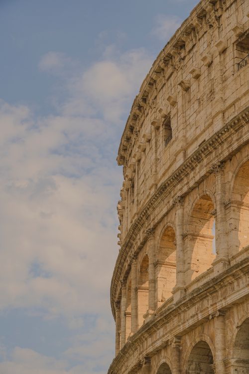 Free Close-up of the Colosseum in Rome showcasing its historic architecture under a blue sky. Stock Photo