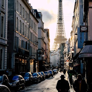 A picturesque Parisian street with the Eiffel Tower in the background during sunset, showcasing urban life.