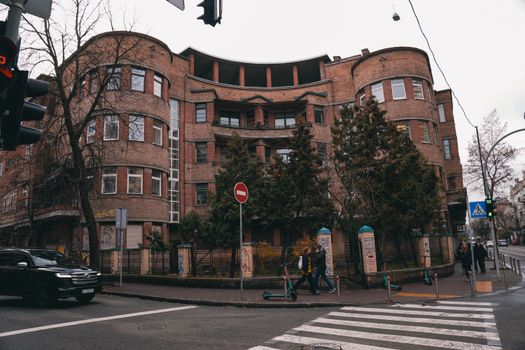 A curved historic brick building on a city street in Kyiv, Ukraine with pedestrians.