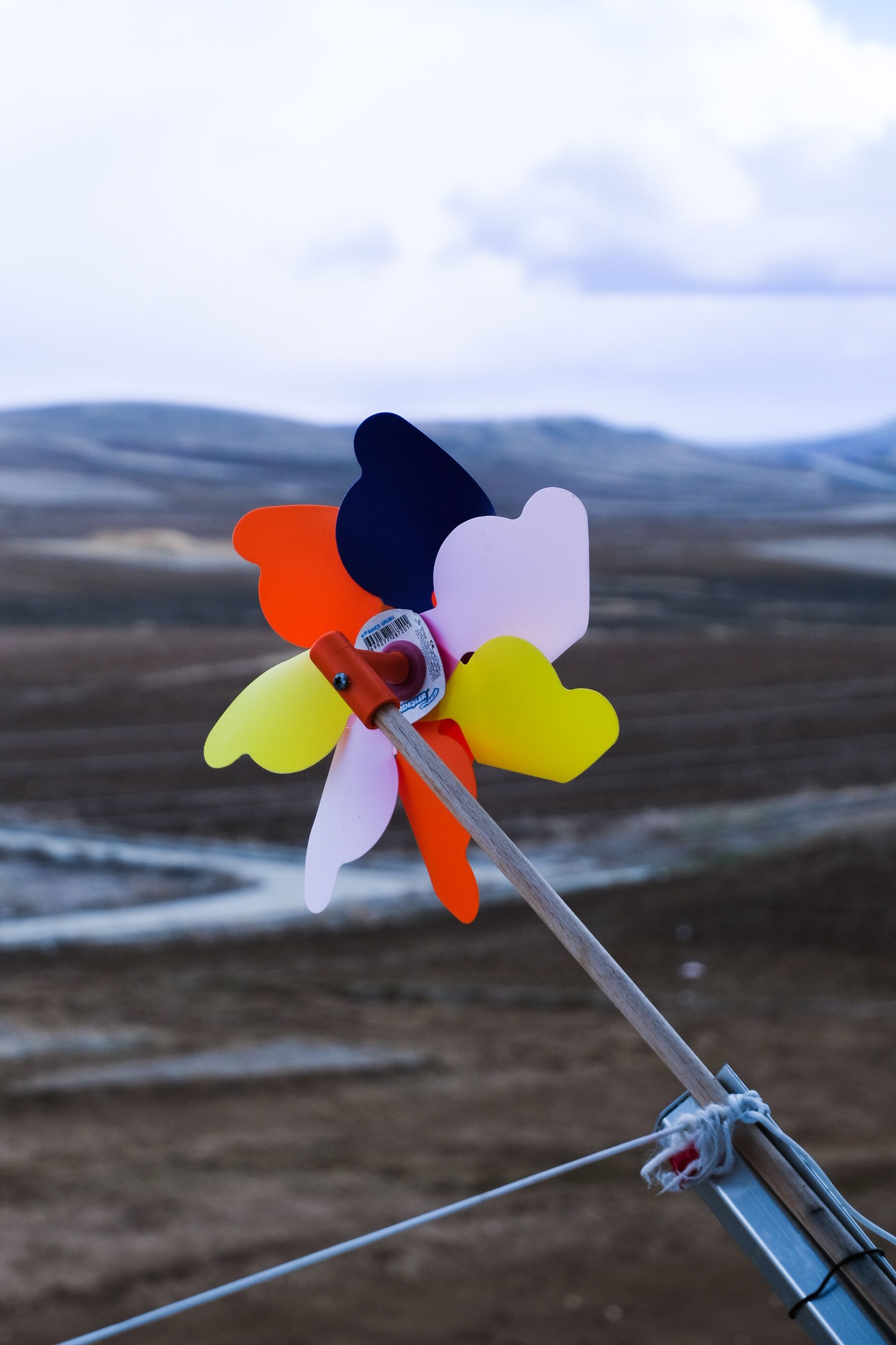 A vibrant pinwheel stands out against a vast outdoor backdrop, capturing a playful contrast.