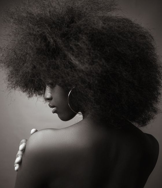 Black and white portrait of a woman with afro hairstyle, turning away.