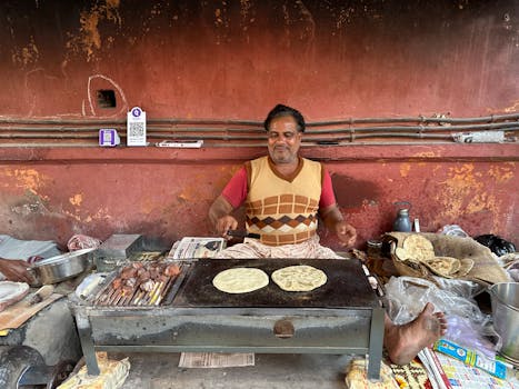 Street vendor cooking Indian flatbread on an outdoor griddle, vibrant market scene.