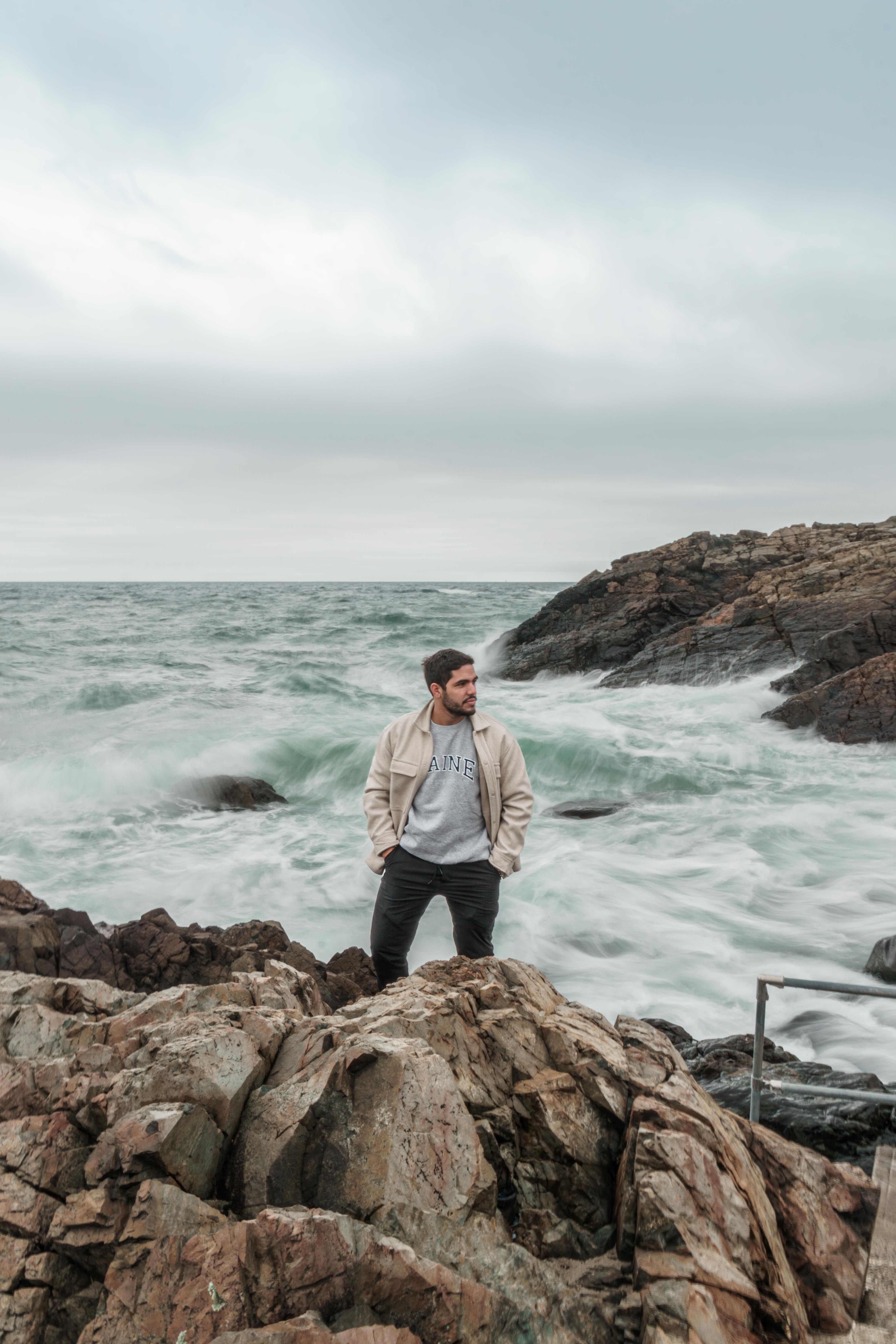 Man Standing on Rocky Shore by Ocean Waves · Free Stock Photo