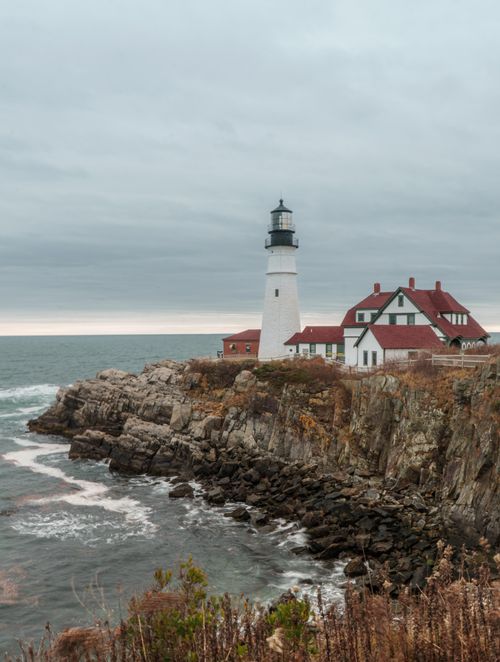 Free Scenic view of Portland Head Light lighthouse on a rocky coastline under cloudy skies. Stock Photo