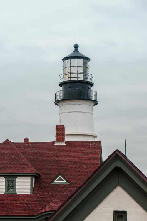 Free Captivating image of a historic lighthouse with a red roof against an overcast sky. Stock Photo