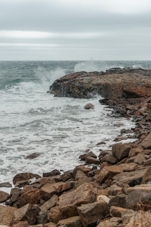Free Dramatic rocky coastline with waves crashing against the rocks and cloudy sky. Stock Photo