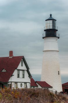 Scenic lighthouse view with adjacent building under a cloudy sky at Cape Elizabeth.