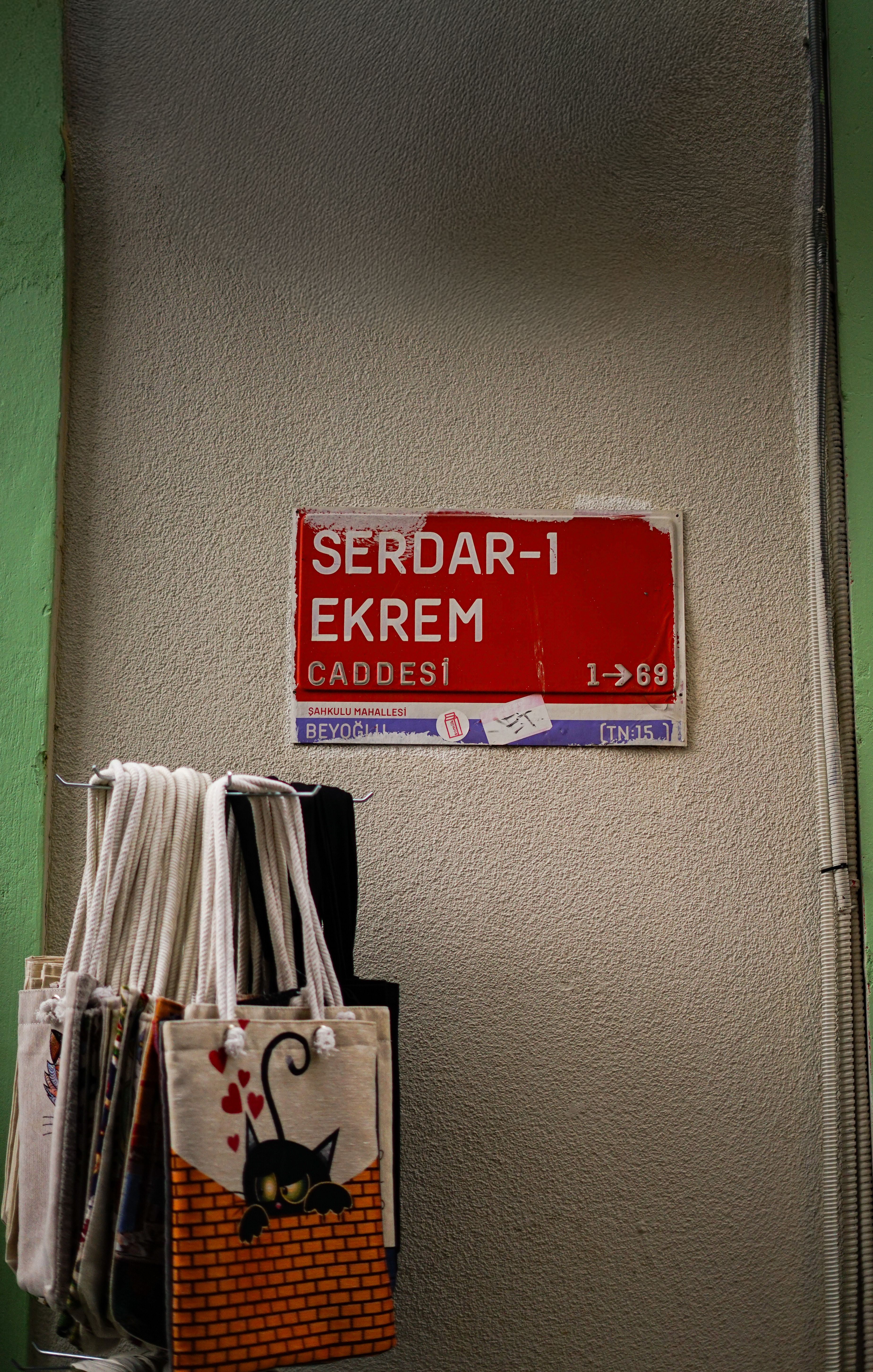 Stylish tote bags hang below Serdar-I Ekrem Street sign in Istanbul.