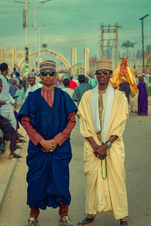 Free Two men in traditional Nigerian attire stand at a cultural festival, showcasing vibrant fashion. Stock Photo