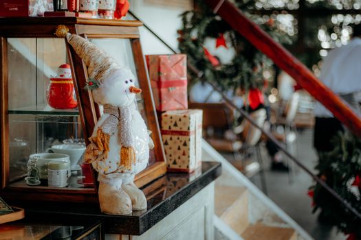 Charming snowman decoration alongside gift boxes in a warm indoor holiday setting.