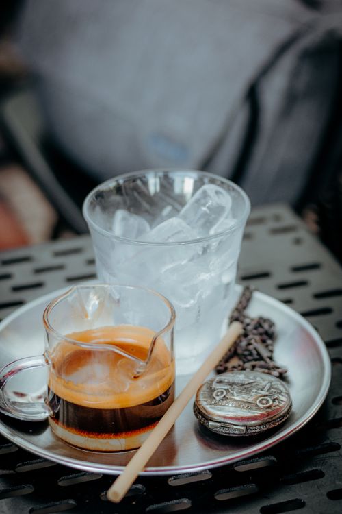 Free Close-up of espresso and ice served on a sleek metal tray with vintage charm. Stock Photo