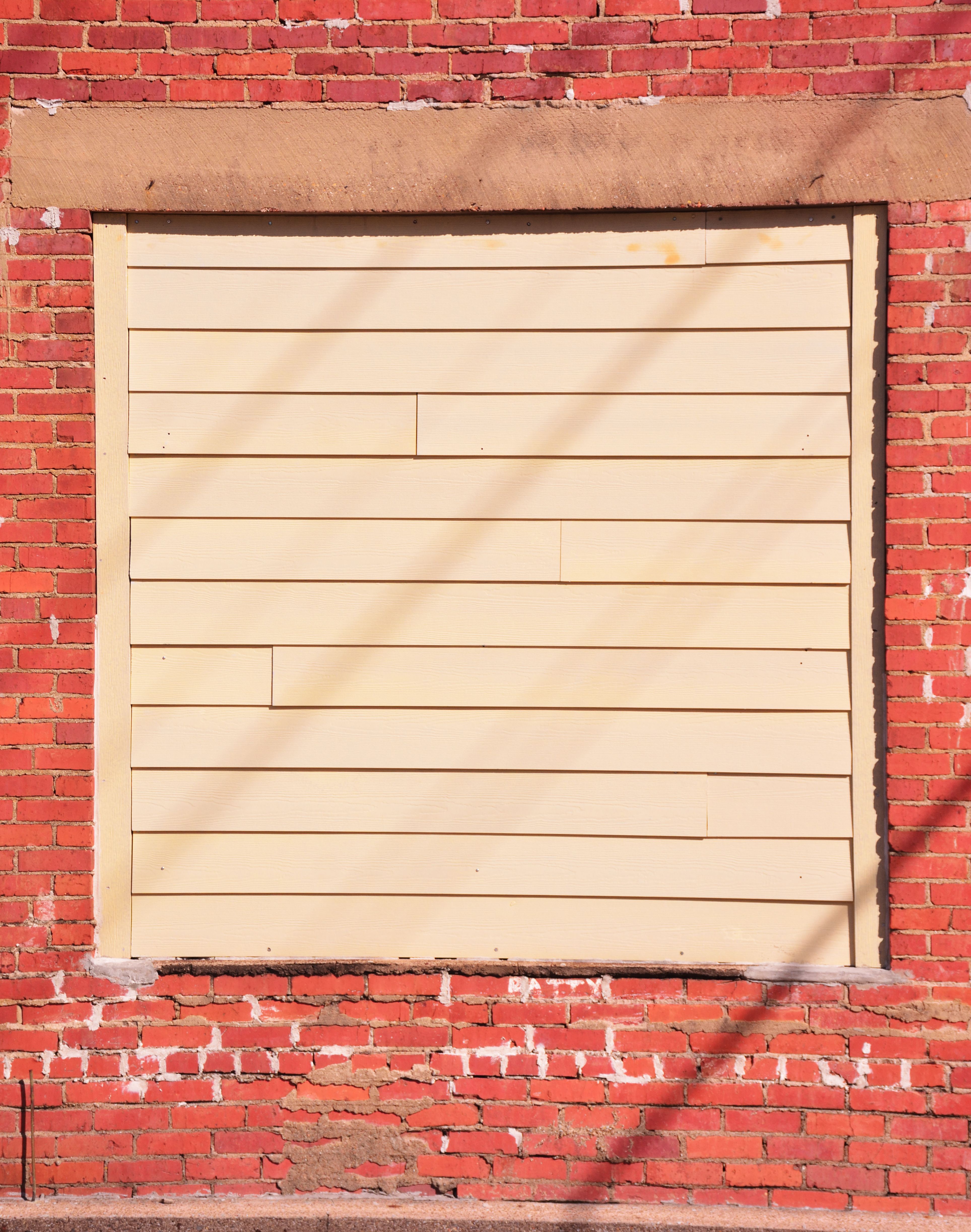 A vintage brick wall with a sealed window in Jacksonville, Texas, captured on a sunny day.