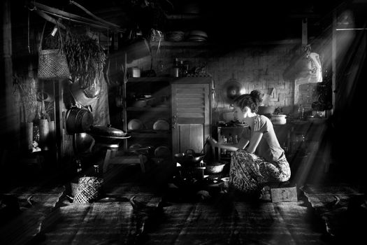 A woman cooking in a traditional West Java kitchen. Rustic and cultural atmosphere.