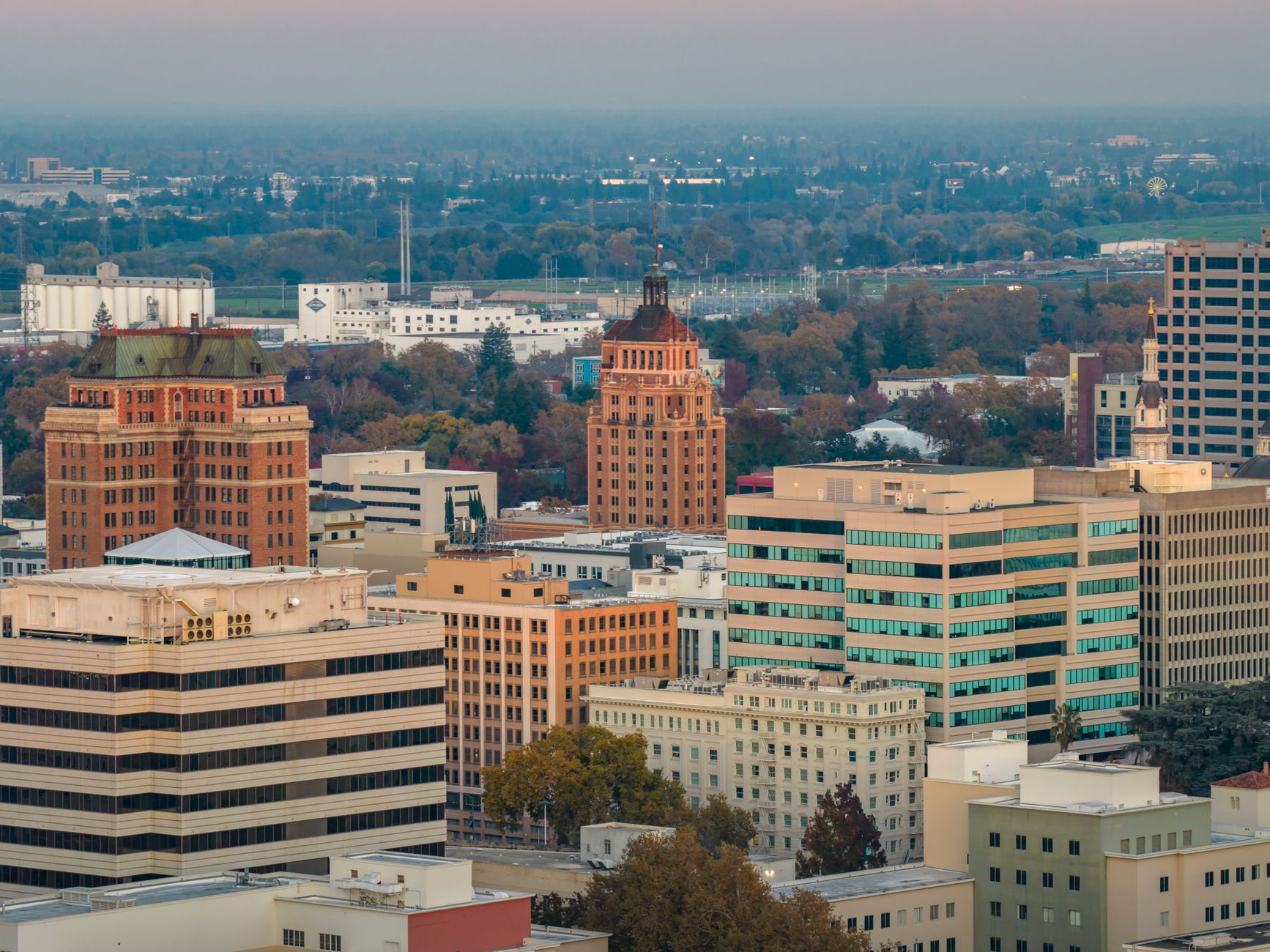 Aerial shot of downtown Sacramento, showcasing iconic buildings and autumn foliage at sunset.