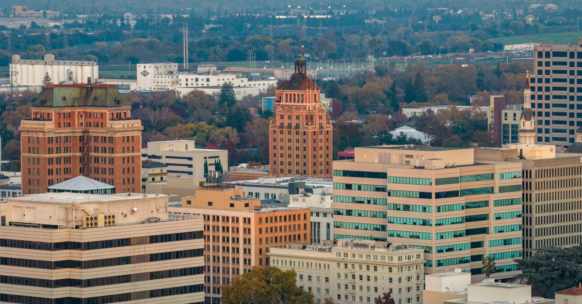 Aerial shot of downtown Sacramento, showcasing iconic buildings and autumn foliage at sunset.