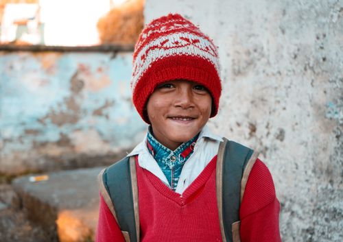 Free Portrait of a smiling child wearing a red knit hat and sweater outdoors Stock Photo