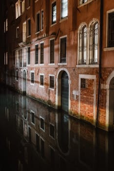 Capture of historic Venetian buildings reflecting in a serene canal at night.