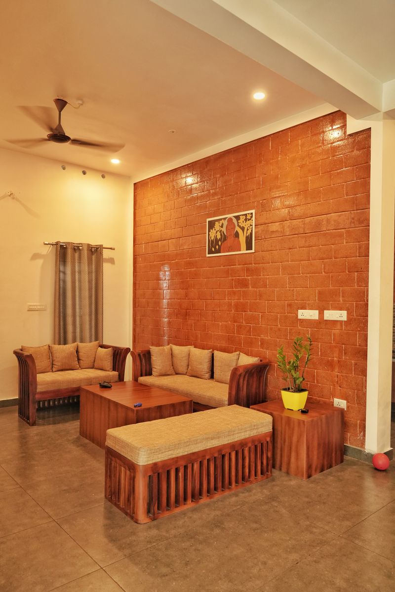 Warm and inviting living room featuring wooden furniture and a brick accent wall in Kerala, India.
