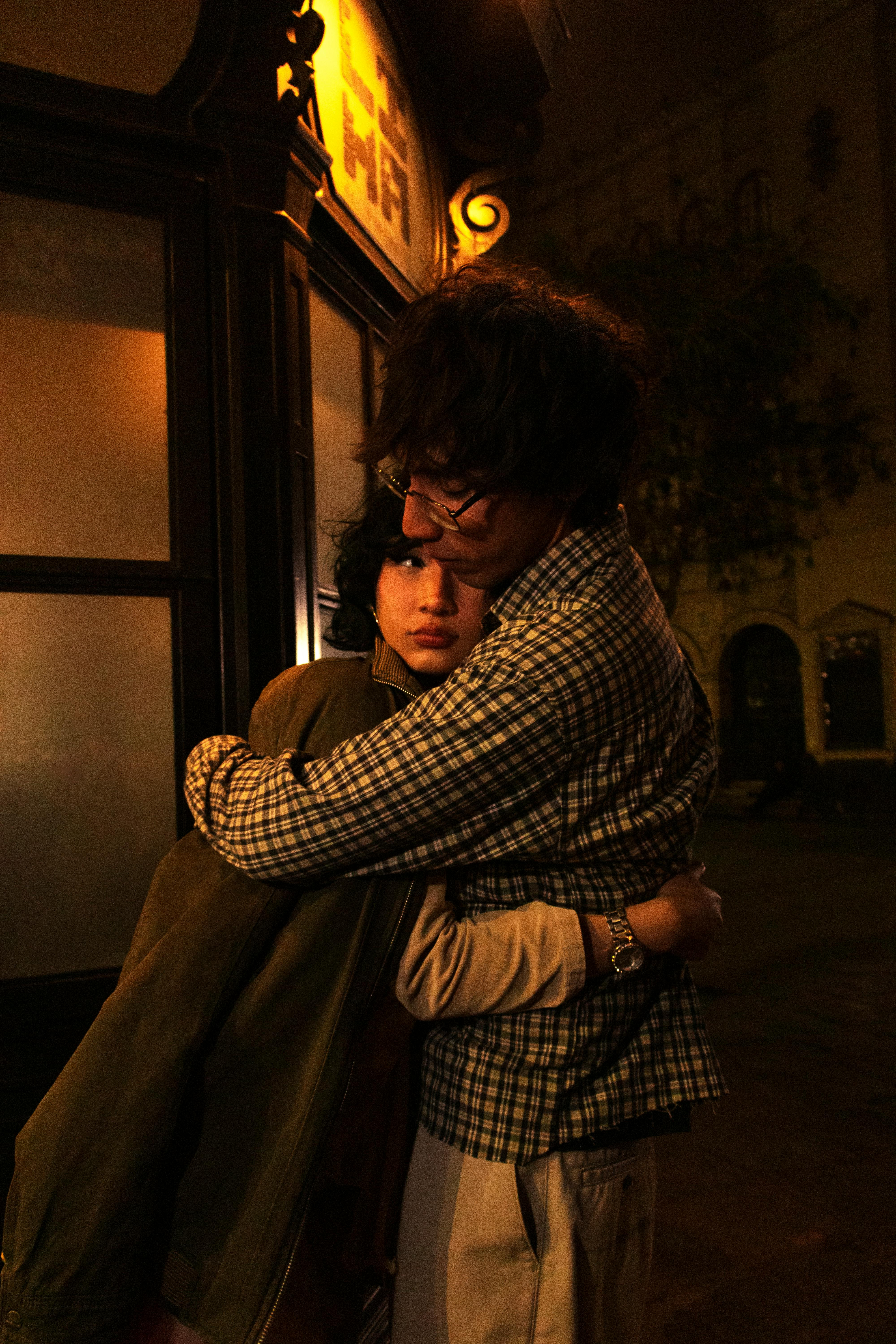Romantic couple embraces warmly on a dimly lit street in Lima, Peru, creating a cozy atmosphere.