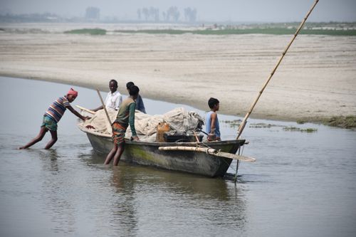 Free Fishermen navigate a traditional boat on a river in Rangpur, Bangladesh, showcasing local livelihoods. Stock Photo