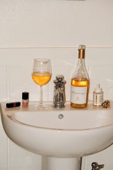 Aesthetic arrangement of wine, cosmetics, and decor on bathroom sink.