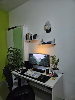 A well-organized modern home office setup with a computer and plants, creating a productive workspace.