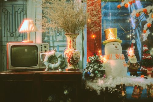 Free A charming retro Christmas scene featuring a snowman, vintage TV, and festive decorations indoors. Stock Photo