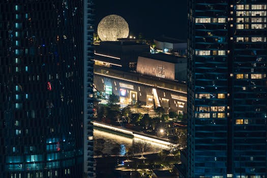 A stunning night cityscape featuring modern architecture and a distinctive spherical structure.