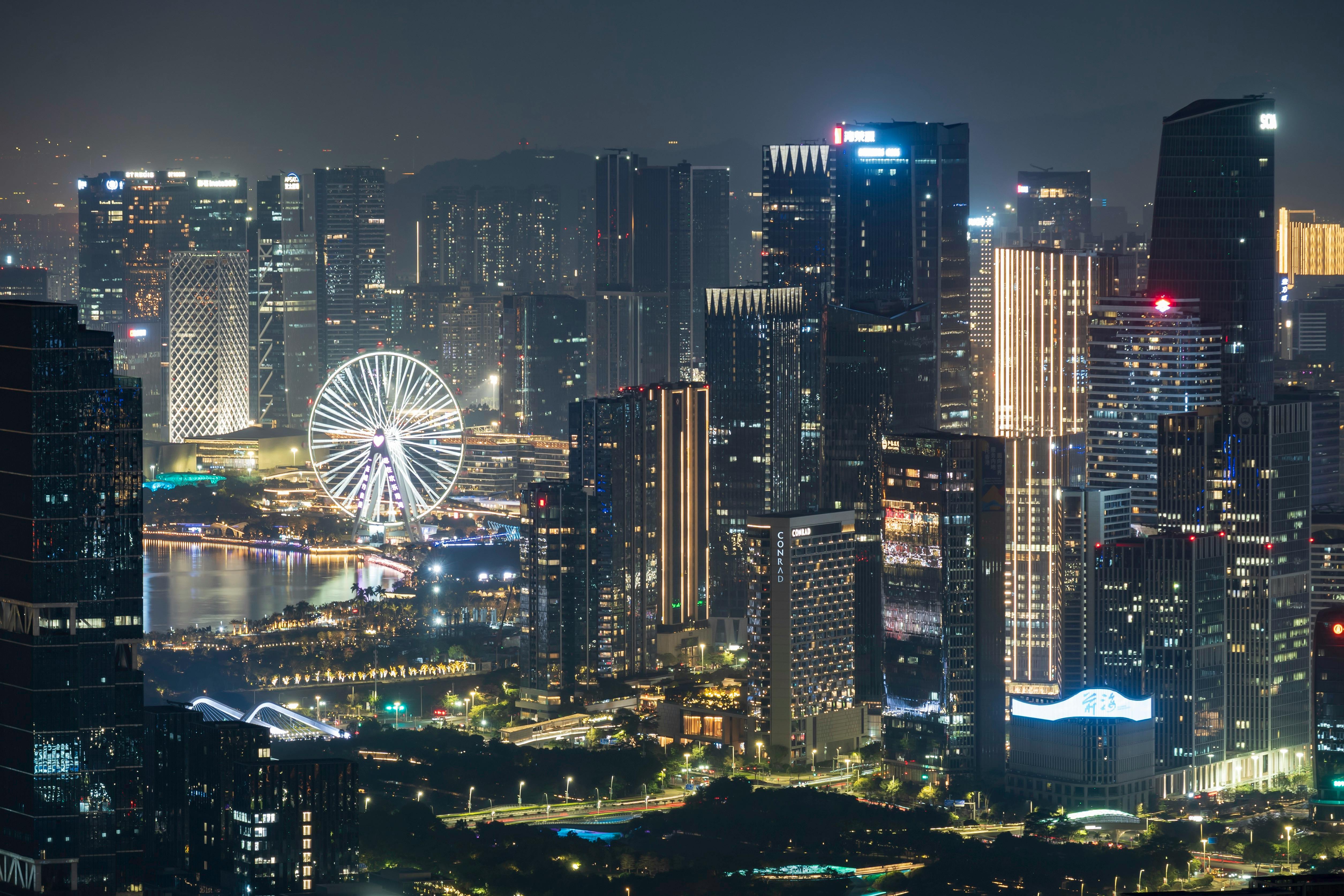 Captivating night view of Shenzhen skyline featuring illuminated skyscrapers and a ferris wheel.