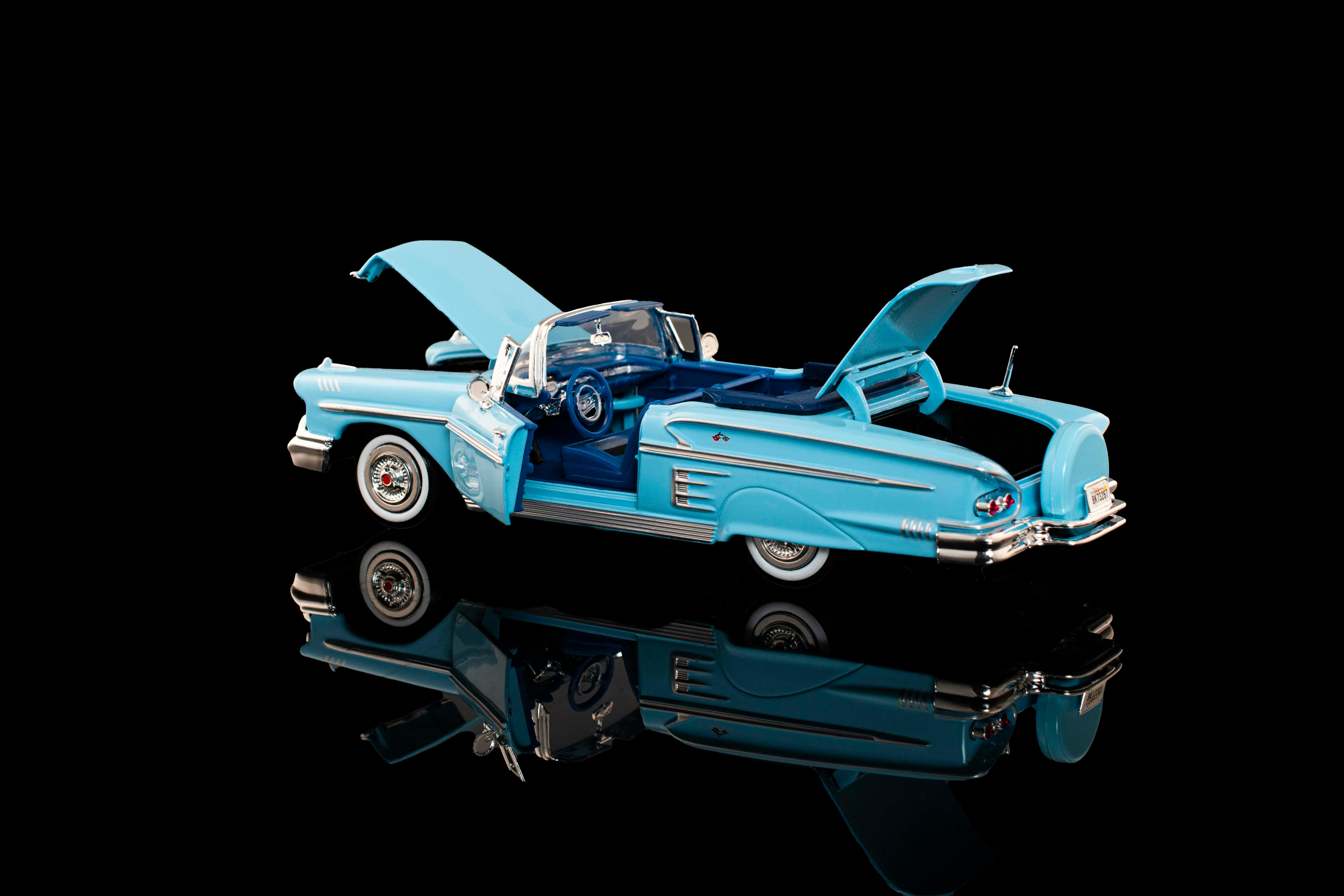 bezplatná Detailní model klasického modrého kabrioletu s otevřenou kapotou a kufrem, zrcadlený na černém povrchu. Základová fotografie