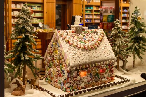 Free Snowy gingerbread house with candy decorations in festive storefront. Stock Photo