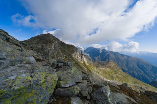 Scenic view of rocky terrain and mountain peaks under a vibrant blue sky in the Swiss Alps.
