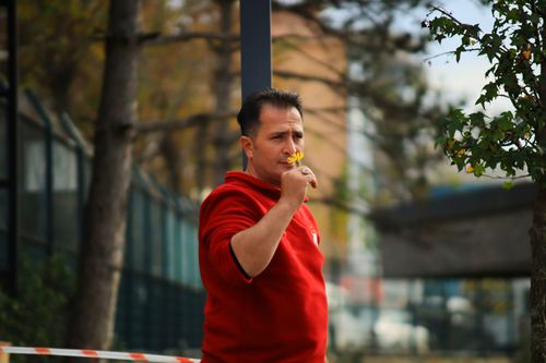 Free Man in red sweater enjoying the scent of a yellow flower in an outdoor setting. Stock Photo