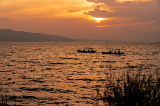 Silhouetted boats on Lake Ulubat during a vibrant sunset in Bursa, Türkiye.