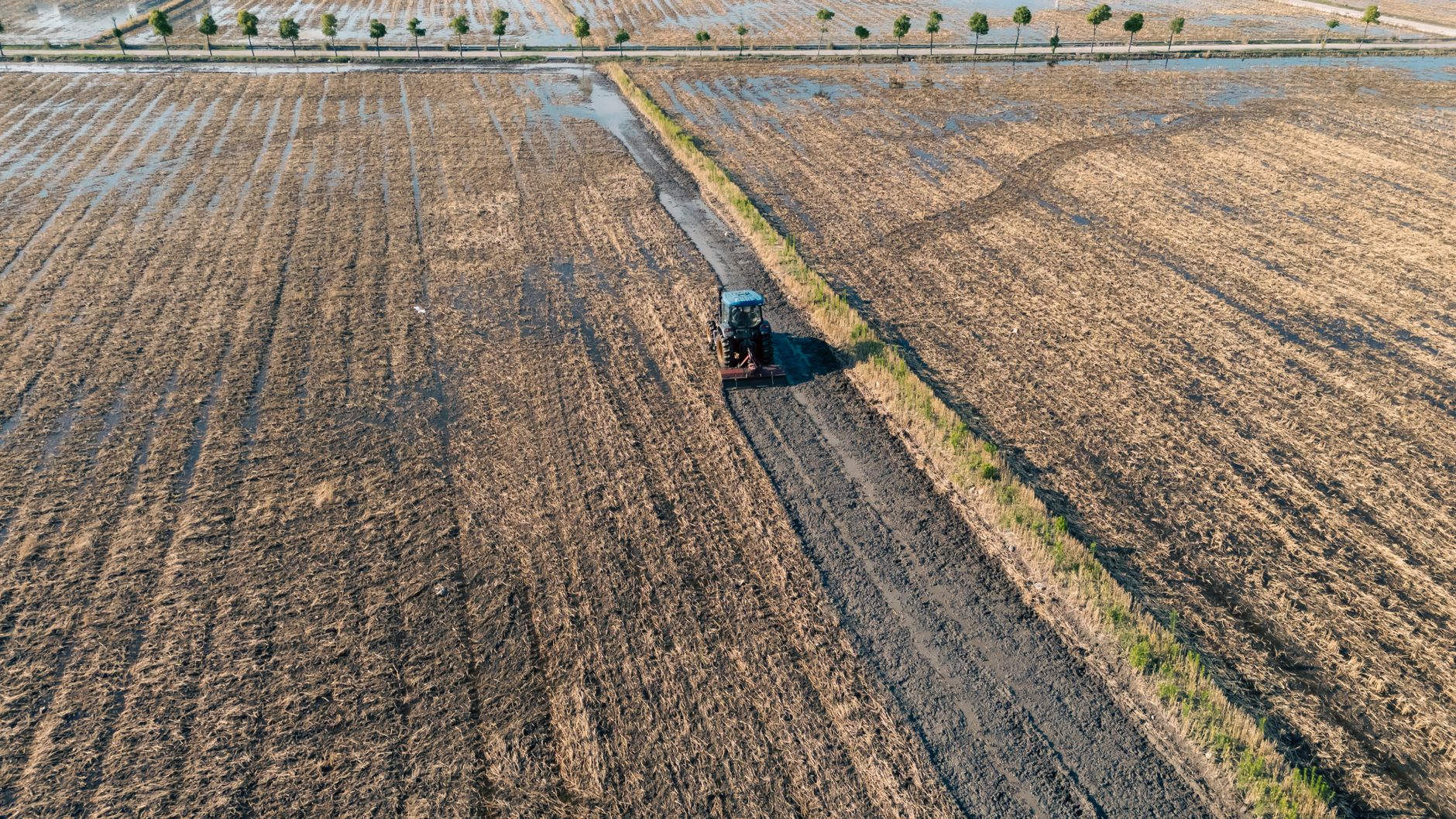 A tractor plows through a rural farmland in Hangzhou, China from an aerial perspective.