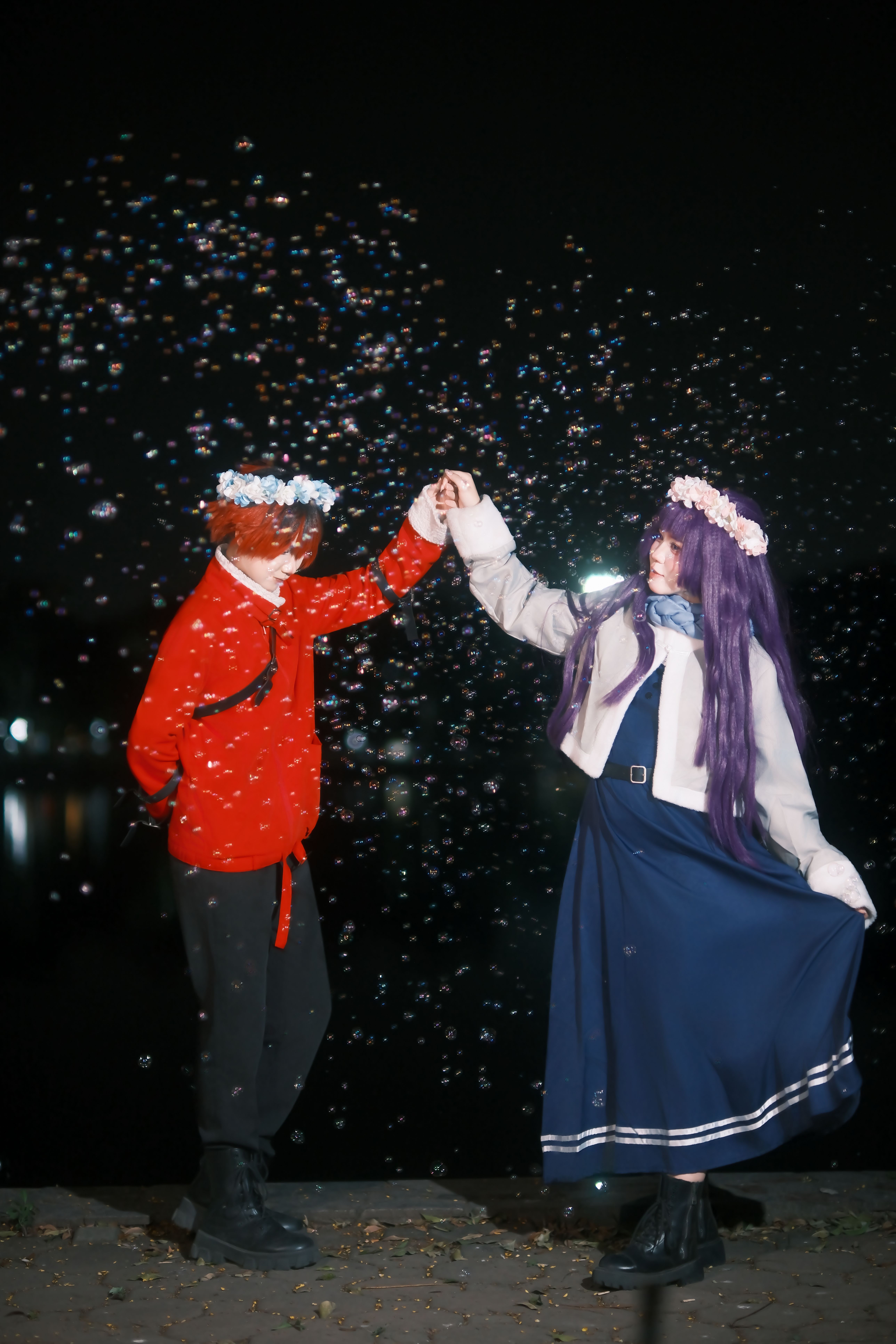 A couple in costume dances at night surrounded by bubbles.