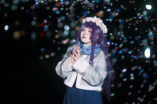 Magical night-time portrait of a woman in floral headpiece with bokeh lights.