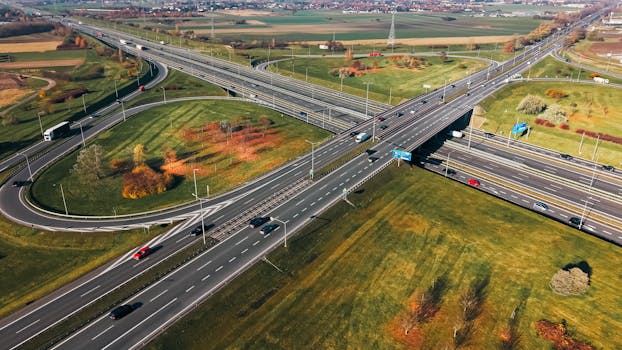 Aerial shot of a traffic-filled highway interchange surrounded by autumn foliage.