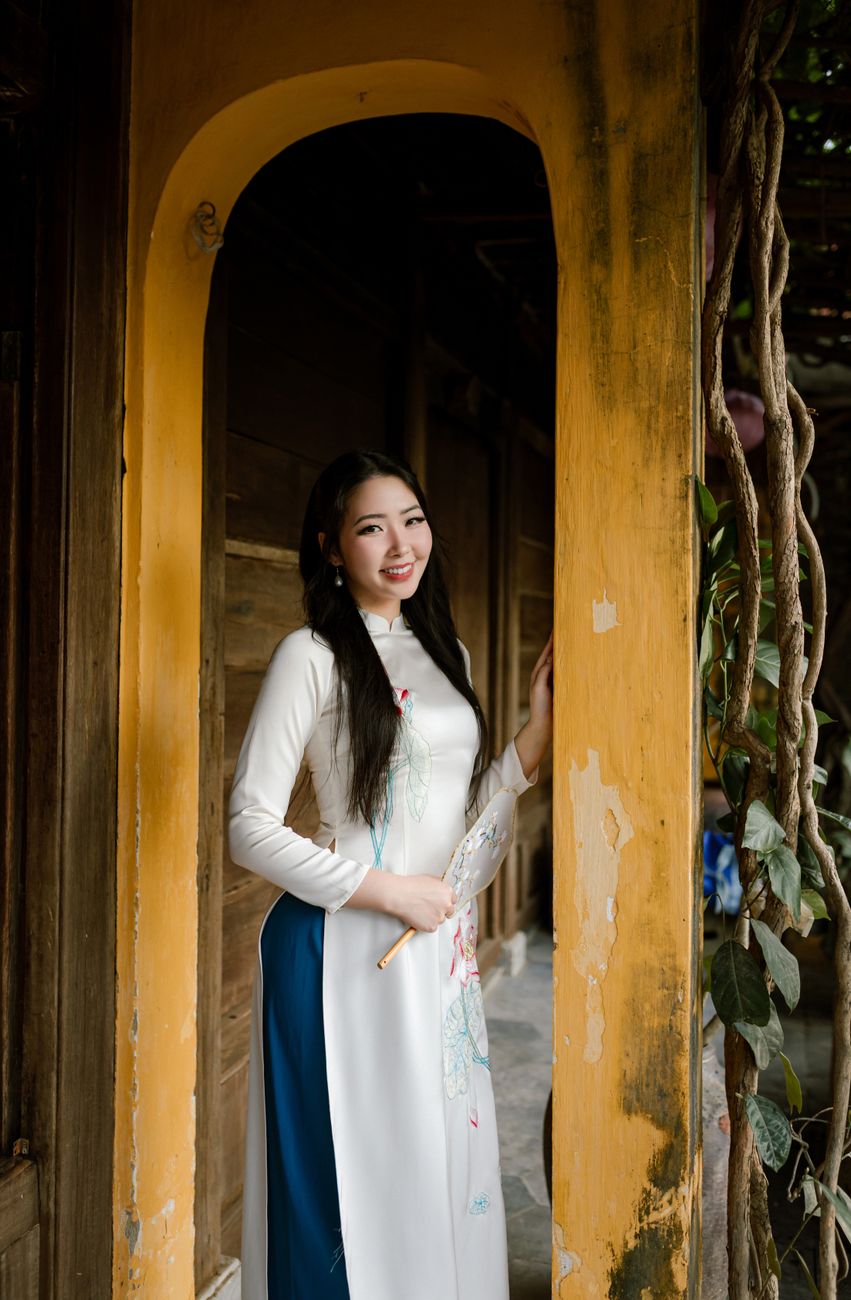 A woman in traditional Vietnamese Ao Dai standing in an archway, Hội An, Vietnam.