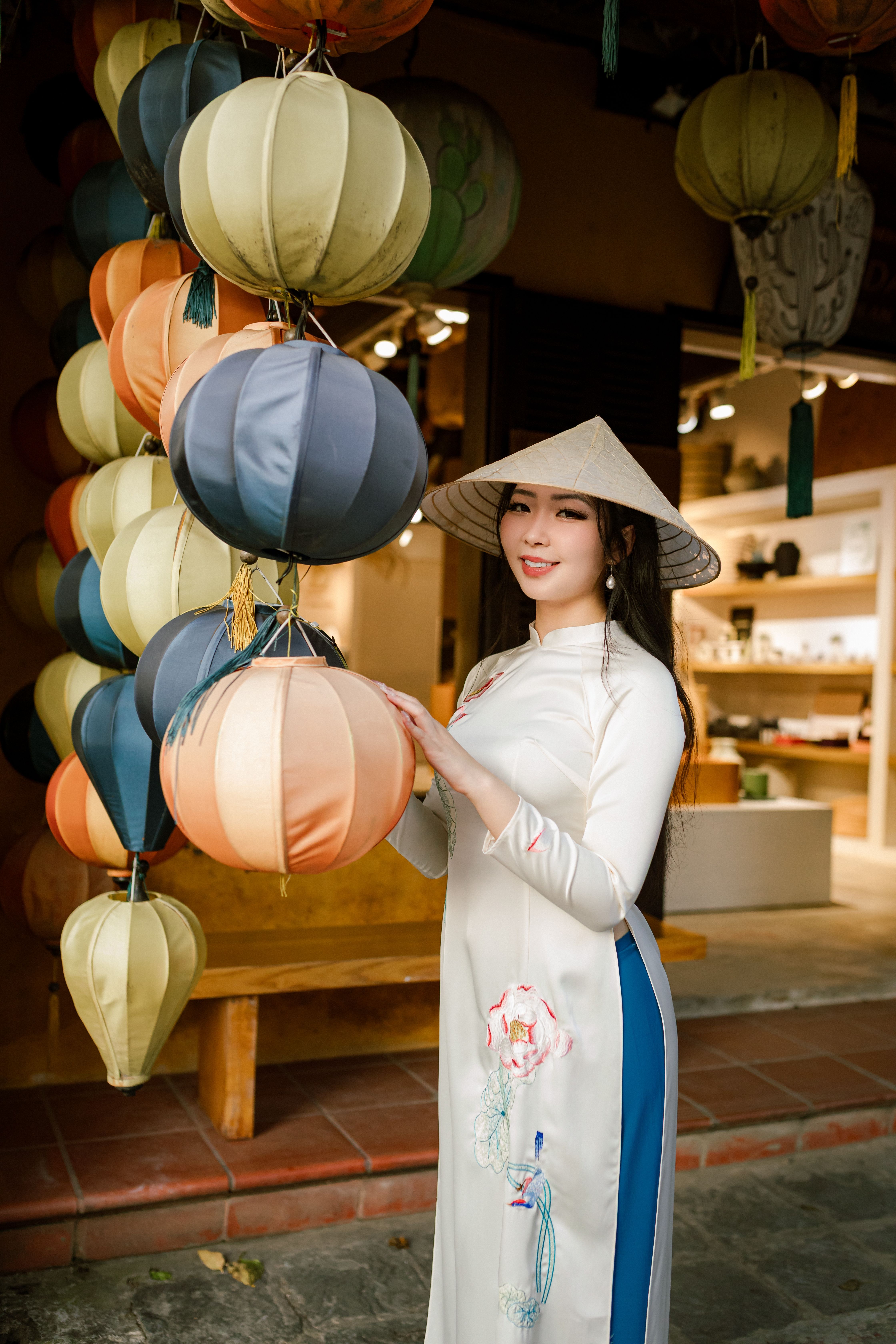 Elegant woman in Ao Dai posing with colorful lanterns in Hội An, Vietnam.