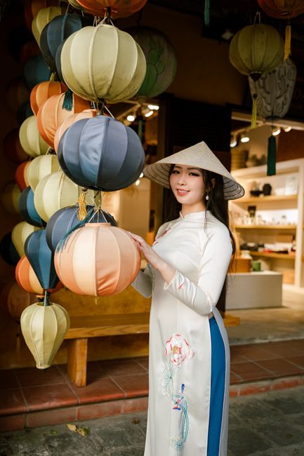 Elegant woman in Ao Dai posing with colorful lanterns in Hội An, Vietnam.