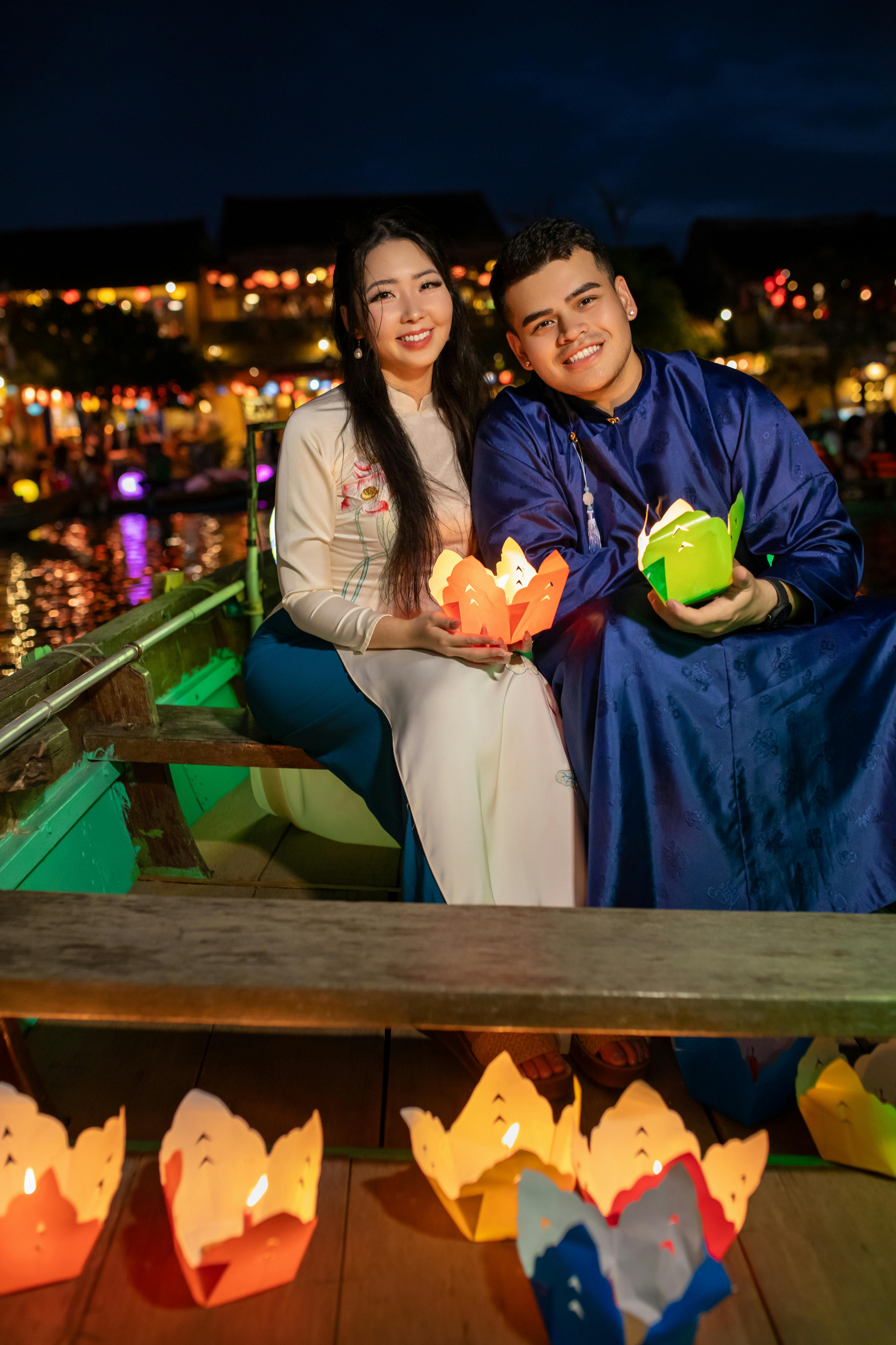 Couple in traditional attire celebrating Hoi An's enchanting lantern festival on a boat.